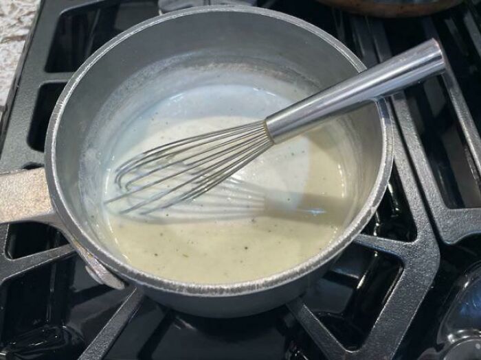 Whisk in a saucepan on a stovetop, demonstrating easy kitchen tricks to improve cooking techniques and kitchen game.