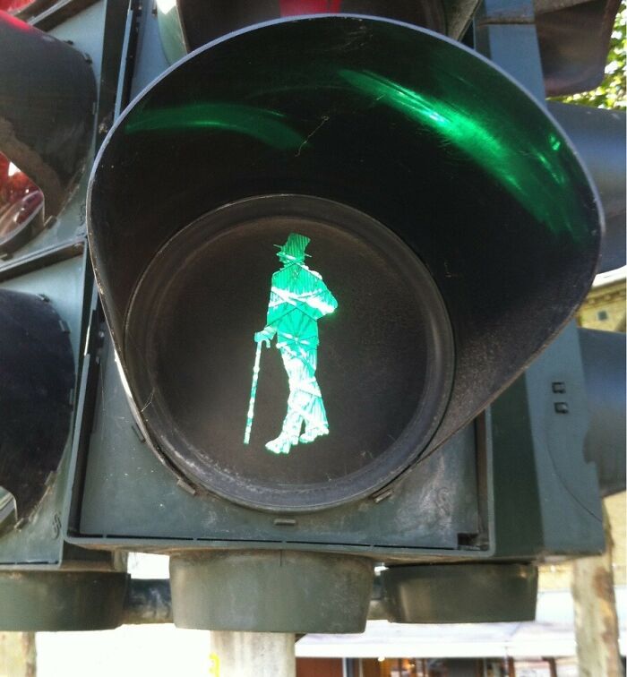 Green pedestrian traffic light in Denmark showing a walking figure with a cane and hat, symbolizing Danish culture.