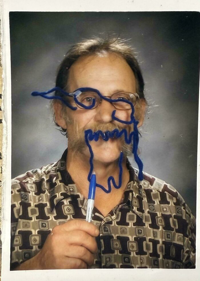 Man holding a blue marker with a funny doodle drawn on his face in a humorous parents photo.