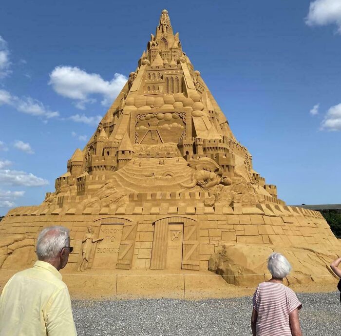 Large detailed sandcastle sculpture with visitors viewing its intricate design, showcasing Danish artistry and craftsmanship.