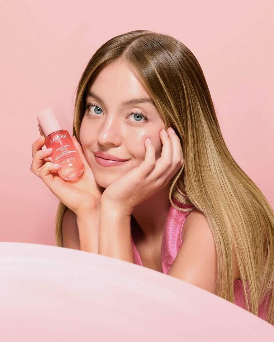 Sydney Sweeney with long hair holding skincare product, representing business ventures and net worth in 2025. Sydney Sweeney with long hair holding skincare product, representing business ventures and net worth in 2025.