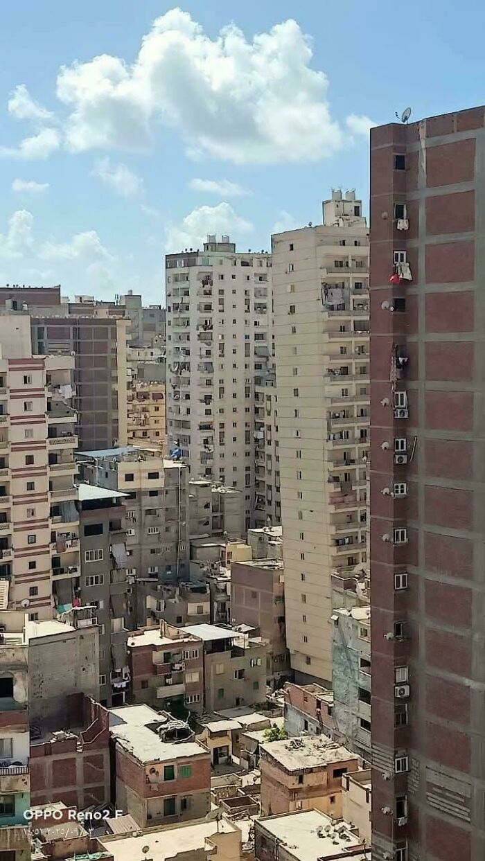 Dense urban apartment buildings with worn facades under a bright sky, illustrating aspects of urban hell in society.