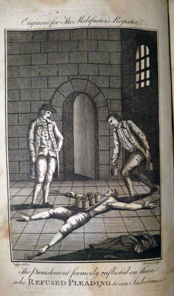Medieval t*****e method illustration showing a restrained man subjected to a t*****e device in a stone chamber.