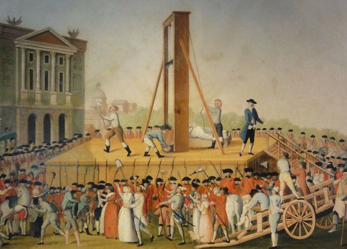 Medieval history scene showing a t*****e device with a crowd gathered for a public punishment event.