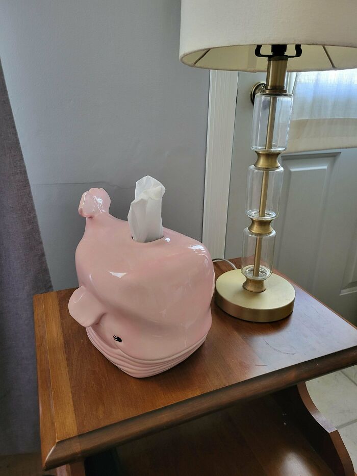 Pink whale tissue holder and glass lamp on a wooden table as unique thrift store finds home decor.