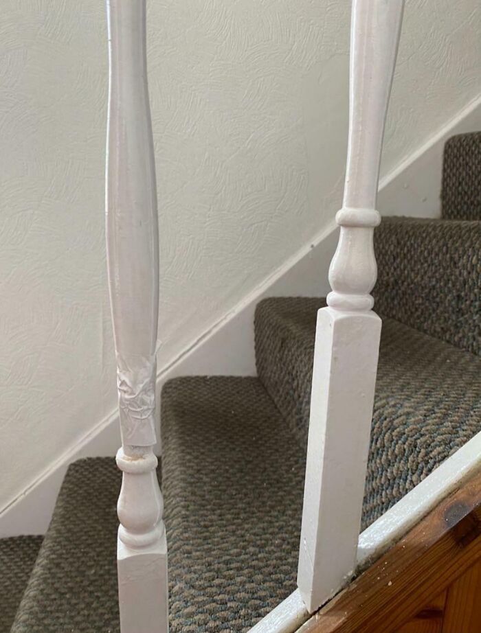 Close-up of a damaged white stair banister showing poor landlord maintenance in a rental property staircase.