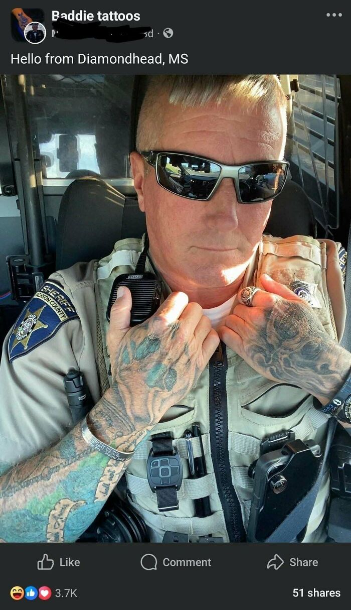 Police officer with extensive hand tattoos wearing sunglasses and tactical gear inside a vehicle, there was an attempt fail pics.