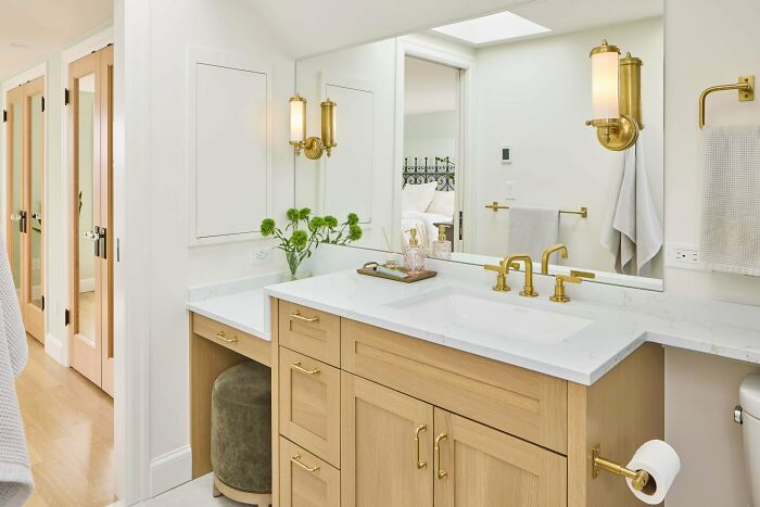 Modern bathroom with wood vanity, gold fixtures, white marble countertop, and decorative plants showcasing home decoration pride.