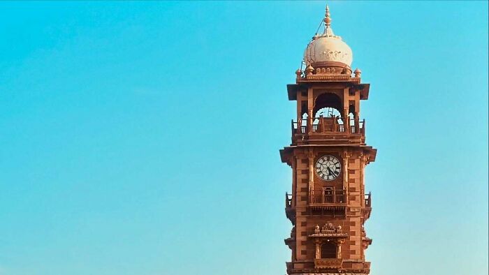 Historic clock tower under clear blue sky, showcasing architecture captured through street photography that captures humanity.