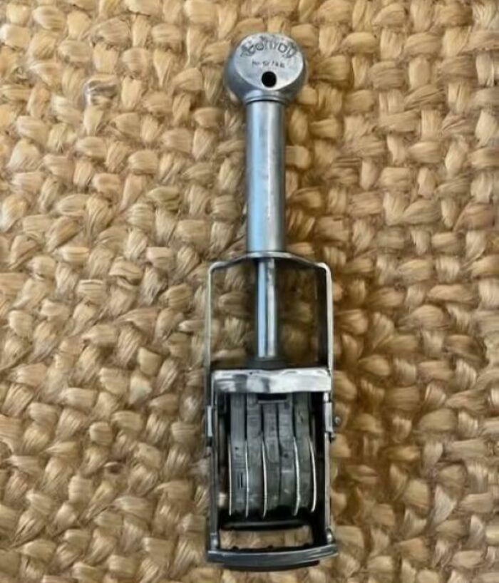 Vintage metal date stamp with rotating number wheels on woven natural fiber surface, evoking nostalgia and old age memories