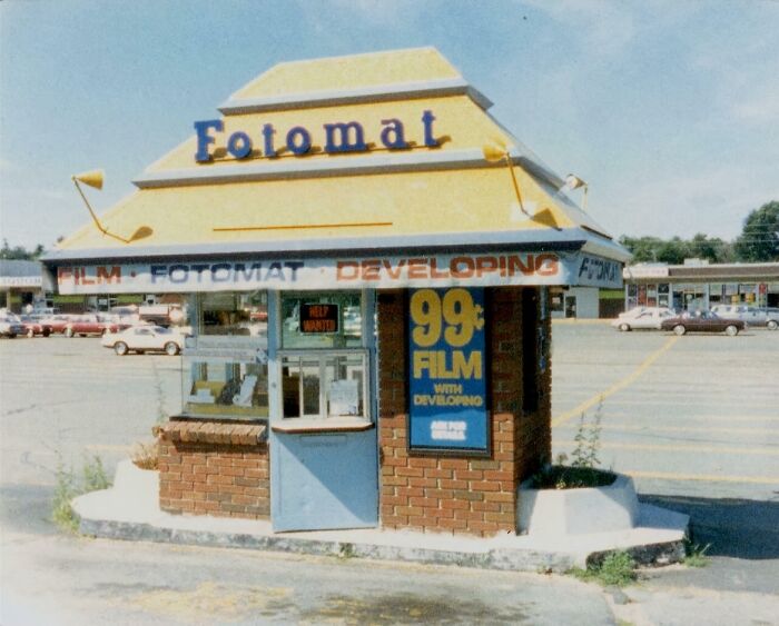 Vintage Fotomat film developing kiosk in a parking lot, evoking nostalgic memories and reminders of old age.