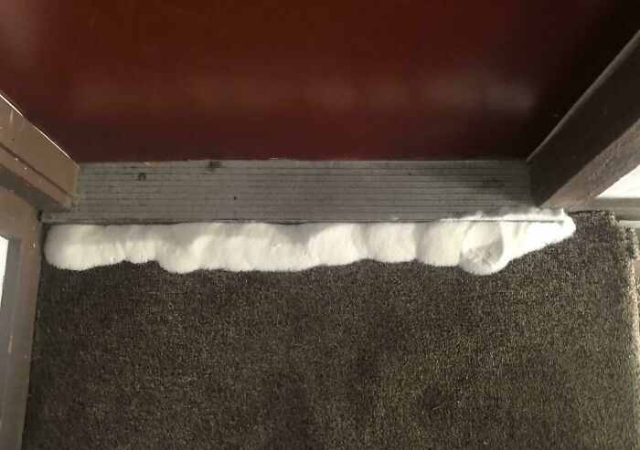 White foam-like substance discovered under door threshold with carpet and metal strip, part of curious things people found.