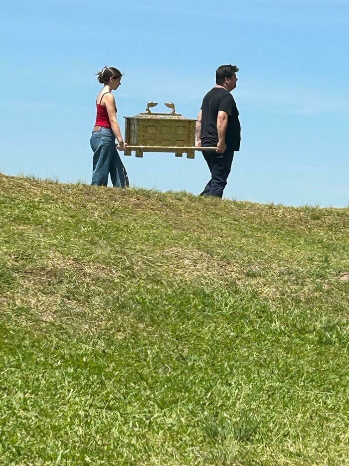 Two people walking on a grassy hill carrying a mysterious ornate box, one of 46 curious things people discovered.