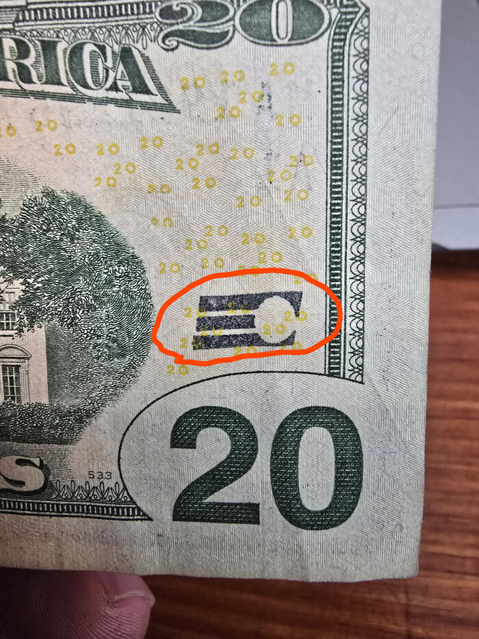 Close-up of a curious thing discovered on a 20 dollar bill, highlighted with a red circle, showing hidden details.