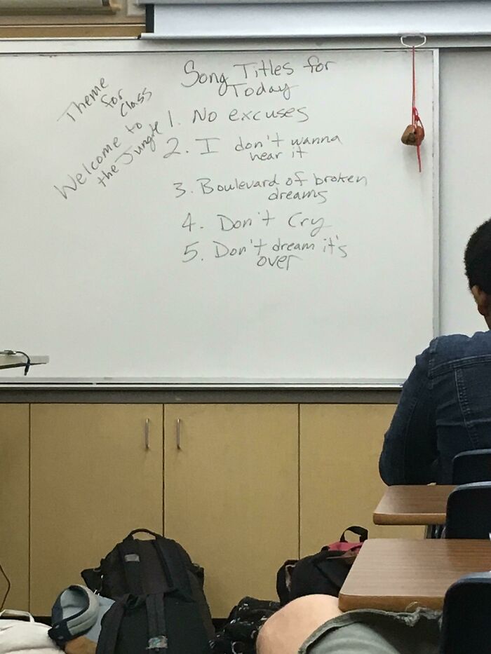 Classroom whiteboard with humorous song titles written by funny teachers for a lighthearted class theme.