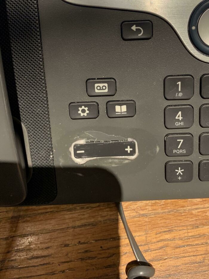 Close-up of office phone with a damaged volume control button, illustrating why people share pics of why they hate their boss.