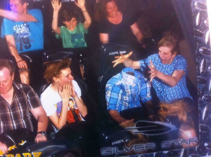 Group of people on an amusement park roller coaster ride reacting with surprise and excitement during the thrilling moment.