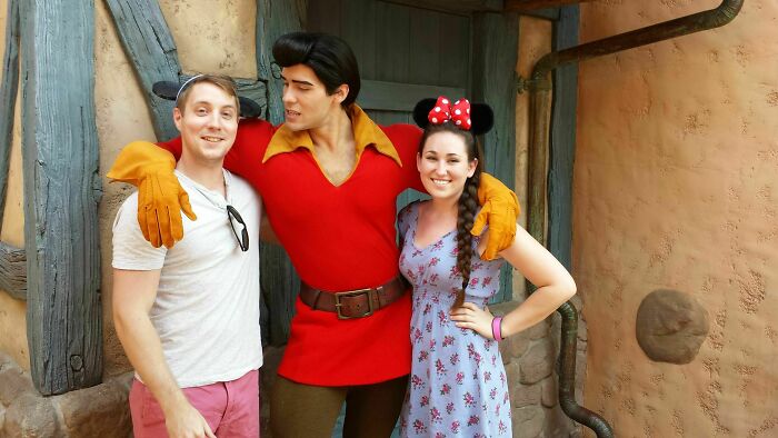 Couple posing with amusement park character in costume, smiling and enjoying their visit at the amusement park.