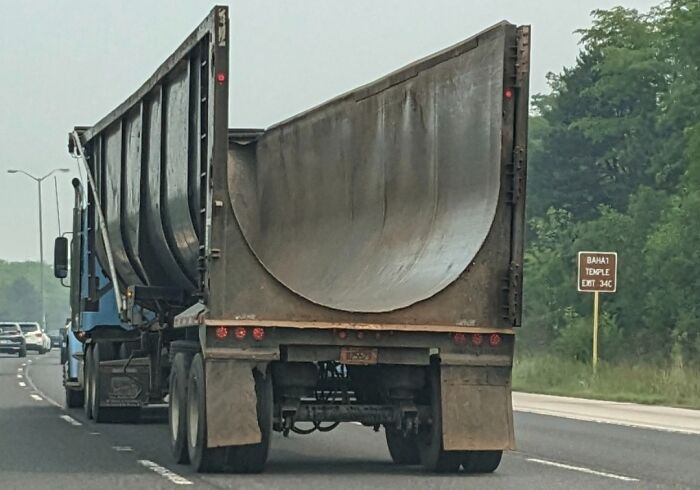 Truck carrying a large curved metal structure on a highway, one of the curious things people discovered and had no idea what they were