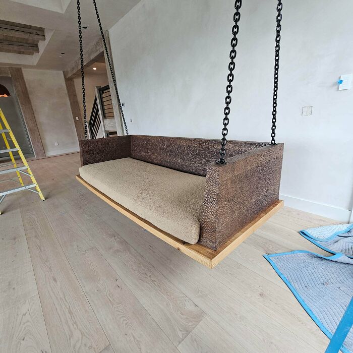 Handcrafted wooden hanging sofa with textured wood panels and beige cushion, showcasing woodworking project excellence.