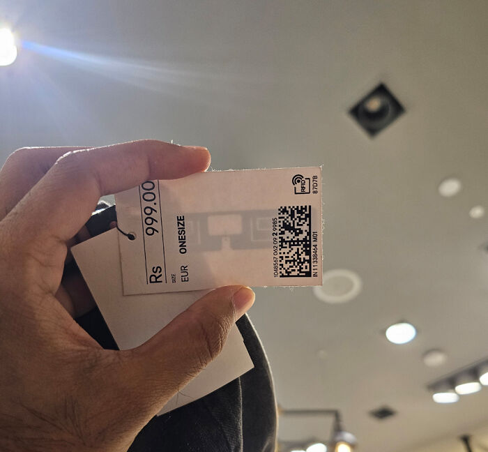 Hand holding a clothing price tag showing an unusually high price, capturing a moderately interesting moment.