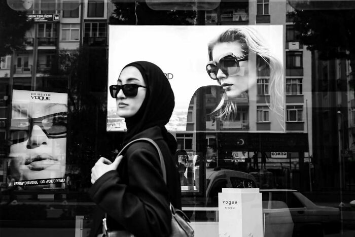 Woman wearing sunglasses and a headscarf walking past perfectly timed street photos by photographer Melahat Ünel.