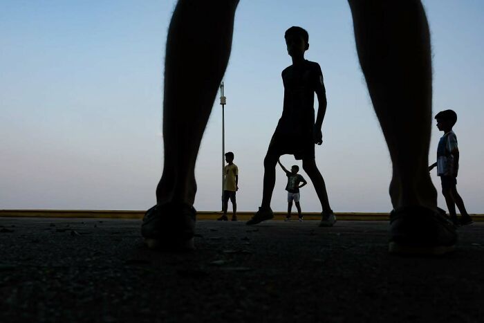 Silhouetted children playing street games at dusk in a perfectly timed street photo by photographer Melahat Ünel.