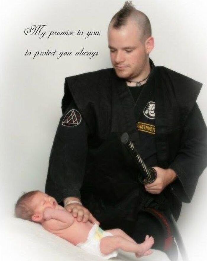 Man in ninja outfit holding a sword and gently touching a newborn baby, capturing cringe-worthy but wholesome moments.