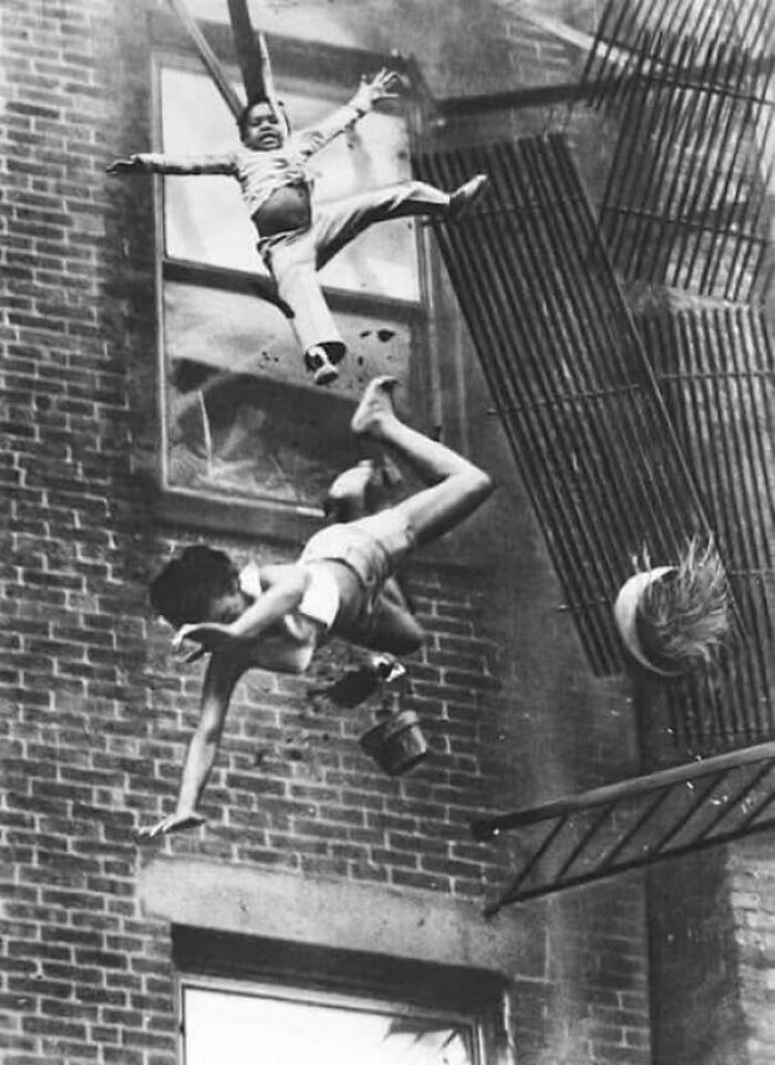 Children falling from a fire escape during an emergency in an old photo showing people's lives from a different time.