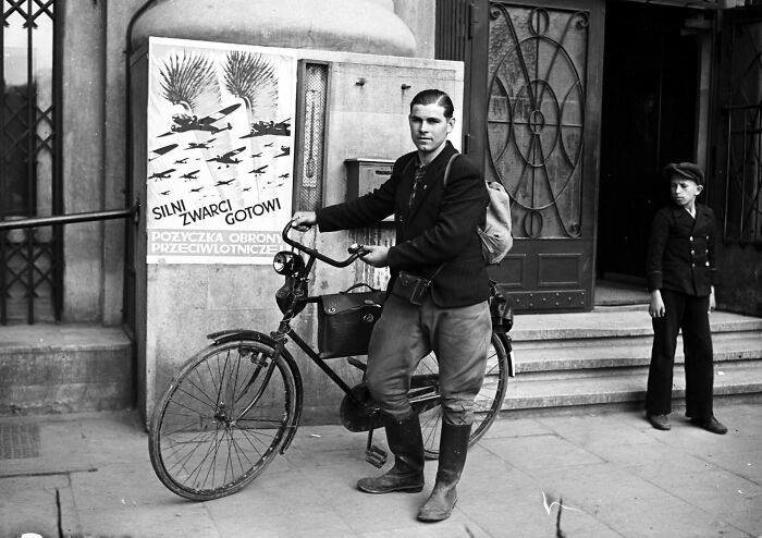 Young man with bicycle outside building in black and white, illustrating old photos depicting people’s lives from a different time.