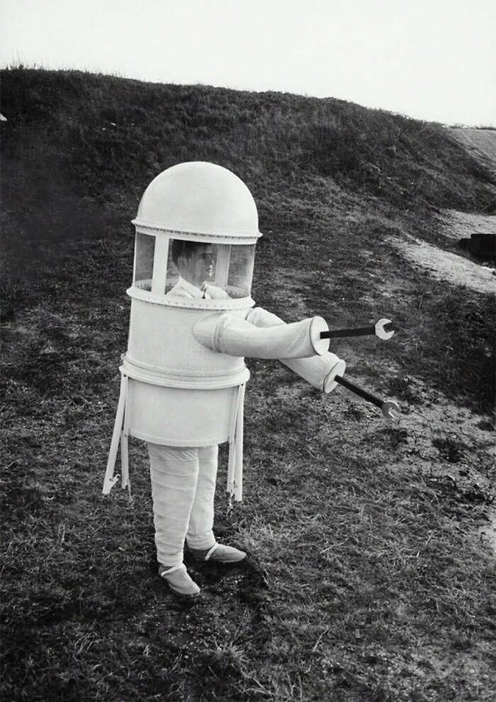 Man in a vintage homemade robot costume with claw arms standing outdoors in an old photo showing people's lives from a different time