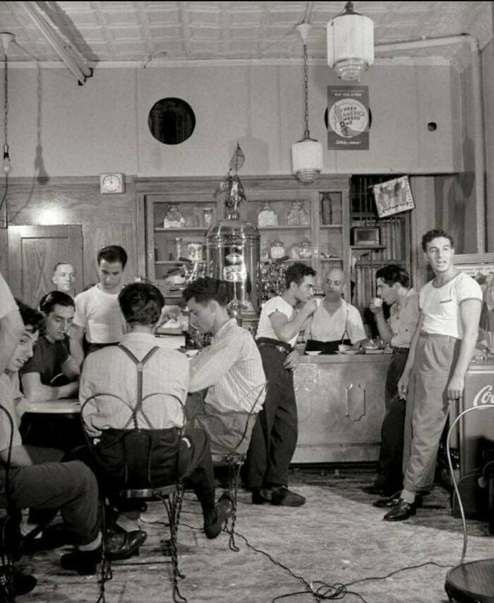 Group of men socializing and drinking coffee in a vintage setting, captured in old photos showing people’s lives from a different time.