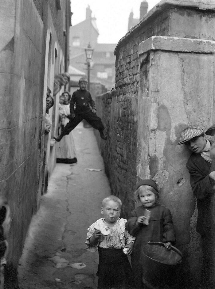 Old photos showing children playing in a narrow alley, capturing daily life from a different time in history.