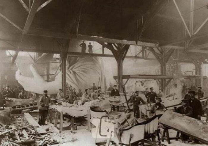 Workers inside a large workshop crafting giant sculptures in an old photo showing people’s lives from a different time.