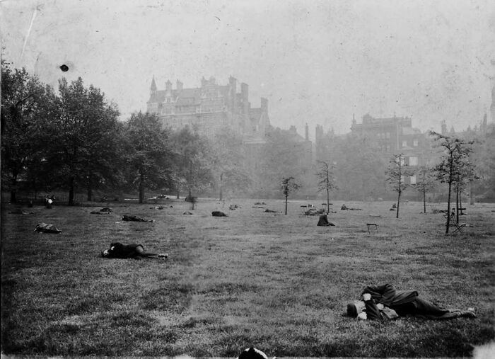 Old photo showing people lying on grass in a park, capturing everyday life from a different time period.