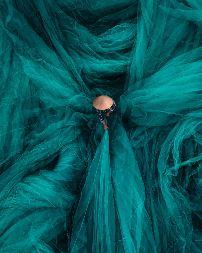Aerial color photography of a person working with large teal nets revealing Earth’s hidden patterns from Refocus 2025 winners.