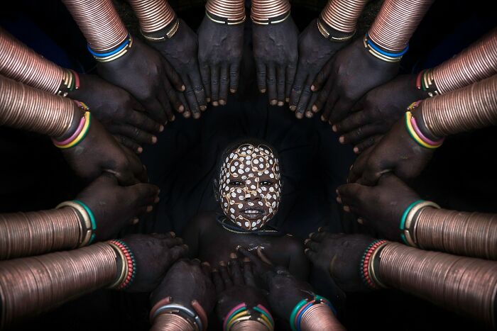 Aerial color photography revealing Earth’s hidden patterns with vibrant tribal body art and circular hand formations.