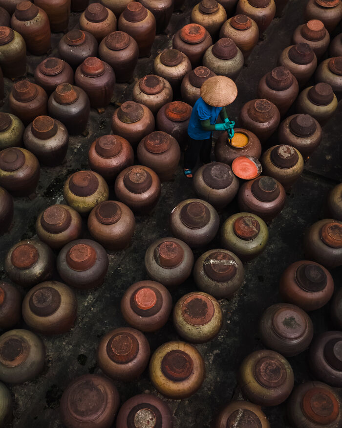 Aerial color photography showing a person among rows of large earthen jars revealing Earth’s hidden patterns.