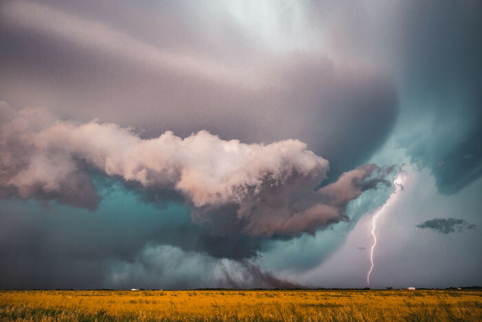 Aerial color photography capturing a dramatic storm with lightning over a golden field revealing Earth’s hidden patterns.