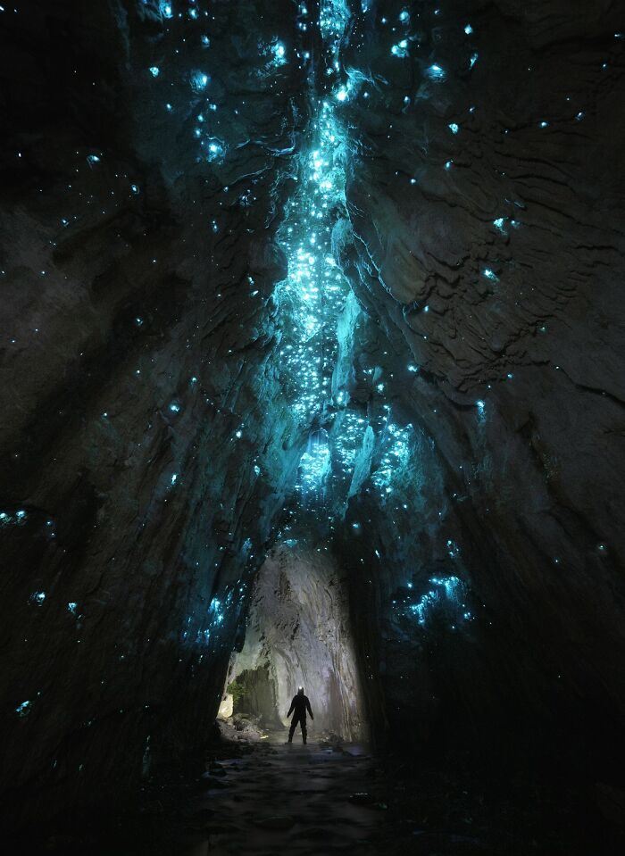A person standing inside a glowing cave filled with blue light patterns revealing earth hidden patterns in aerial photography.