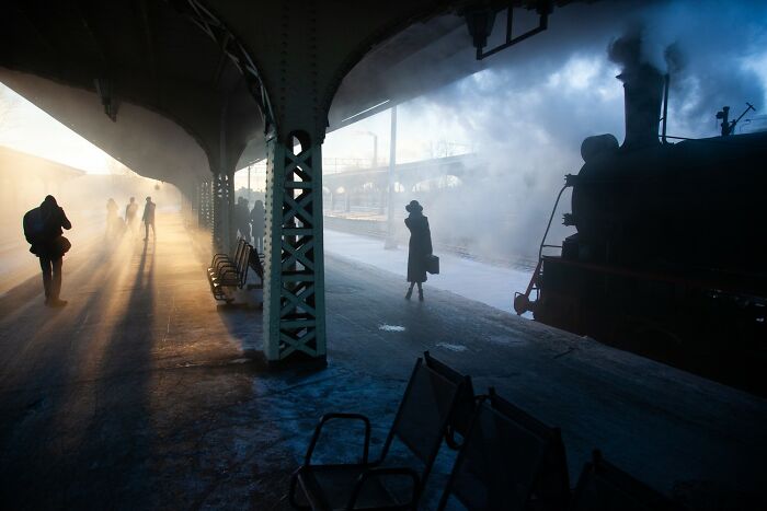 Aerial view showing earth’s hidden patterns with atmospheric light and steam at a train station platform at sunrise.
