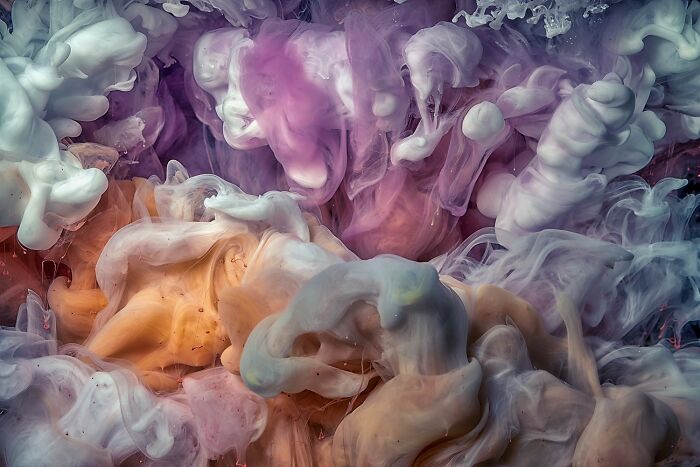 Aerial color photography revealing Earth's hidden patterns in swirling vivid clouds of pink, purple, orange, and white hues.