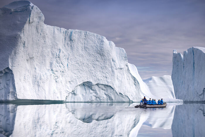 Aerial view of explorers in a boat navigating icy waters showcasing Earth’s hidden patterns in color photography.