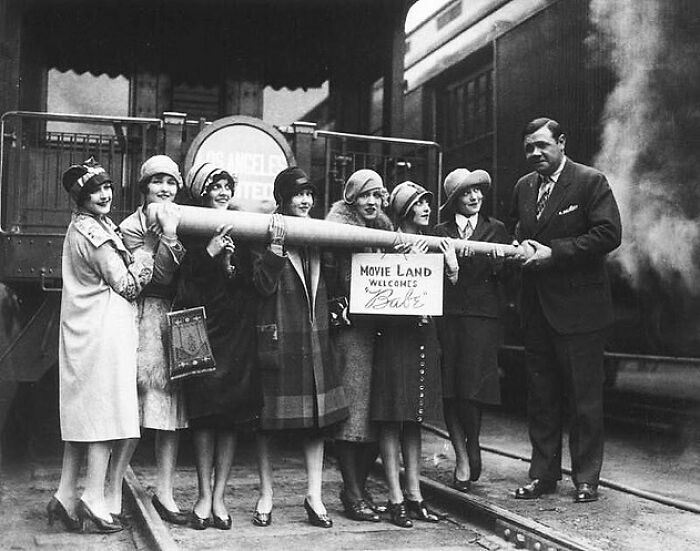 Group of women and a man holding a large telescope in old photo showing people’s lives from a different time.