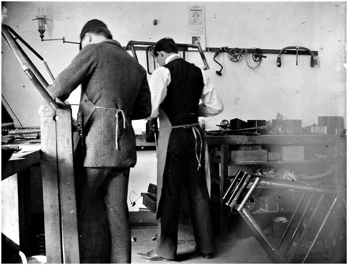 Two men working in a workshop, showcasing old photos capturing people’s lives from a different time.