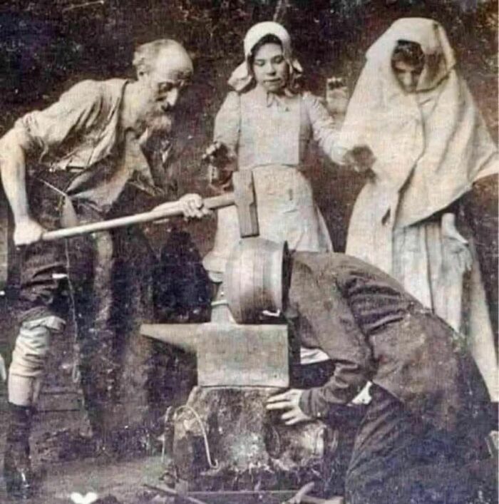 Old photo showing a blacksmith at work with people observing, illustrating people's lives from a different time period.