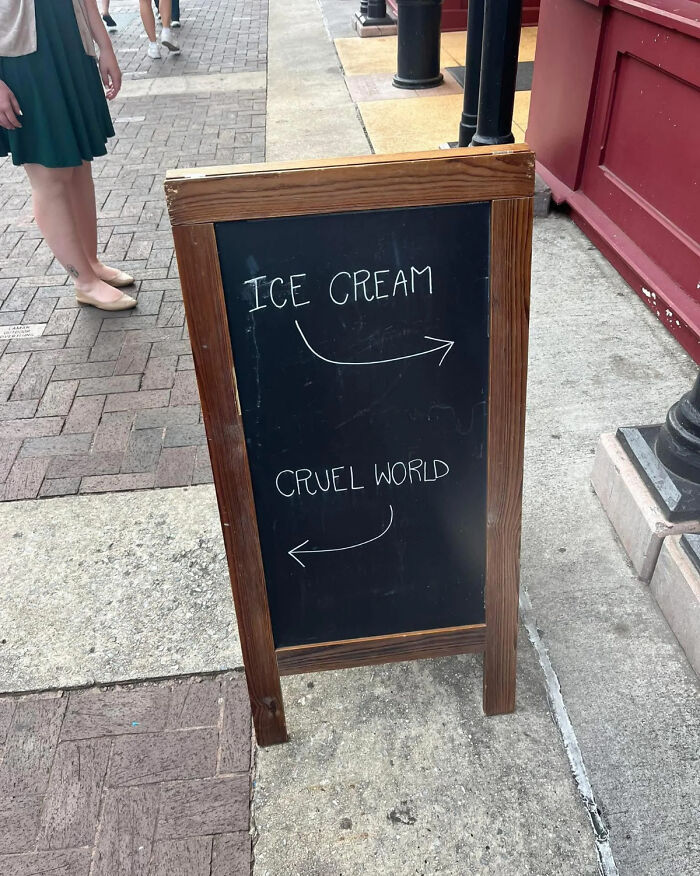 Sidewalk chalkboard showing funny and bizarre signs directing to ice cream and the cruel world outdoors.