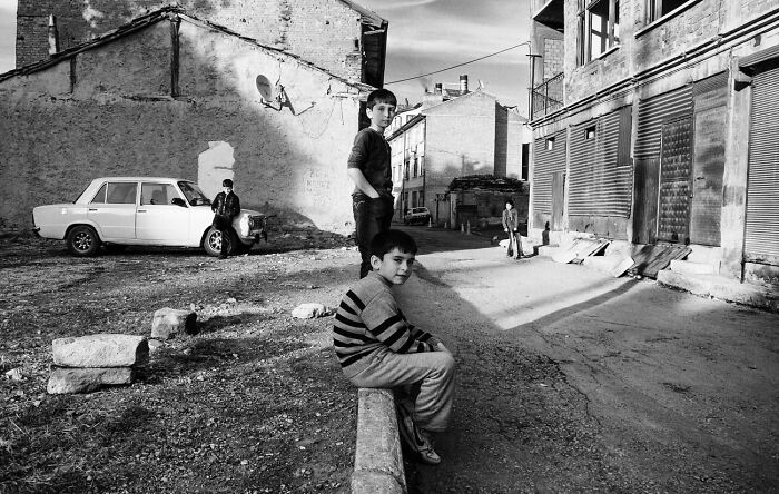 Black and white candid photo showing children in a quiet street, capturing the real side of life in Turkey by Yusuf Aksoy.