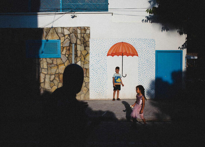 Children playing near a colorful mural with an umbrella in a candid street photo showcasing life in Turkey.