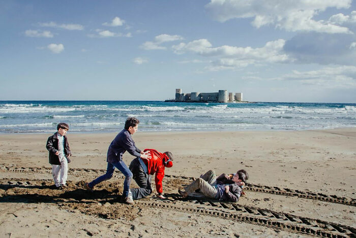Children playing on a sandy beach in Turkey near an ancient castle, capturing the real candid side of life.